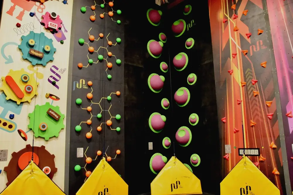 Four of the themed Fun Walls side by side: giant cogs, a molecule pattern, bubbly planets and a speed wall with a timer